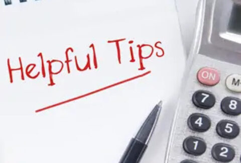Open notebook with 'helpful tips' written on page and pen and calculator on top