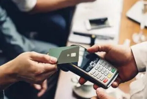 Person using bank card to make a contactless payment at card machine