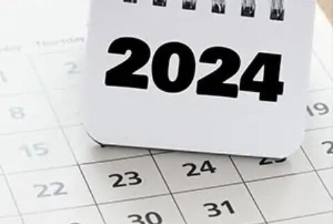 Calendar page with smaller ring bound notebook balanced on top reading '2024'