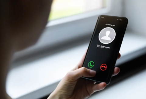 Hand holding smartphone displaying incoming call from unknown number