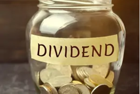 Glass jar half-filled with coins with 'dividend' label on front