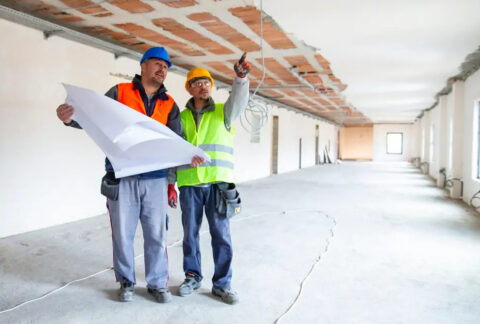 Two construction subcontractors at a building site discussing plans