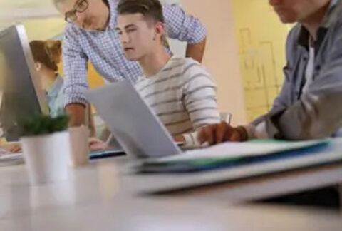 Senior businessman supervising junior colleague at desk
