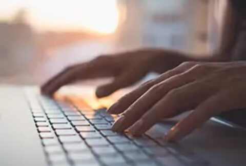 Hands typing on laptop keyboard