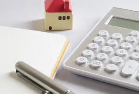 Empty notebook and pen, miniature model house and calculator