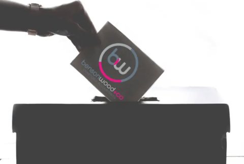 Hand inserting voting slip with Benson Wood & Co Chartered Accountants on it into ballot box