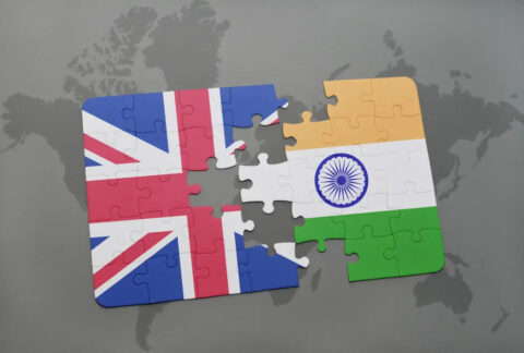 Almost completed jigsaw split down middle with UK flag on one side and India flag on the other