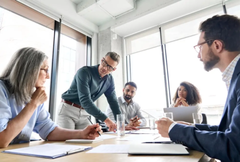 Businessman talking to employees around table in meeting