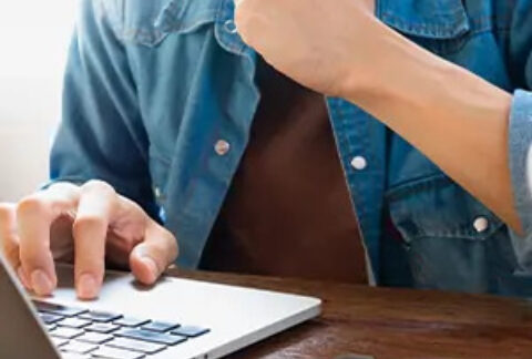 Man using laptop with pile of coins beside