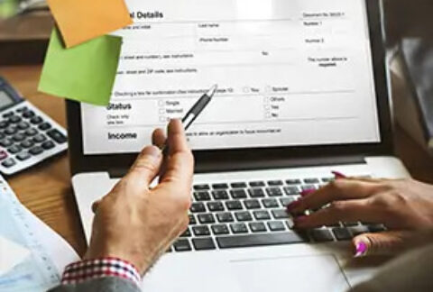 Two businesspeople filling out a tax return on laptop