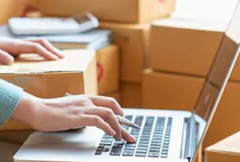 Woman working on laptop surrounded with cardboard boxes