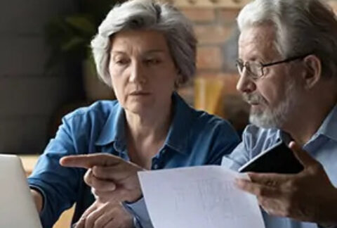 Two elderly people looking and pointing at laptop screen
