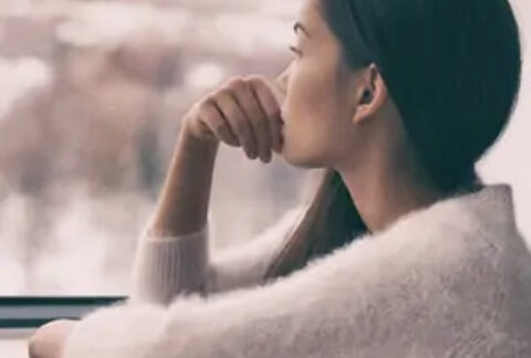 Woman sitting at window staring outside