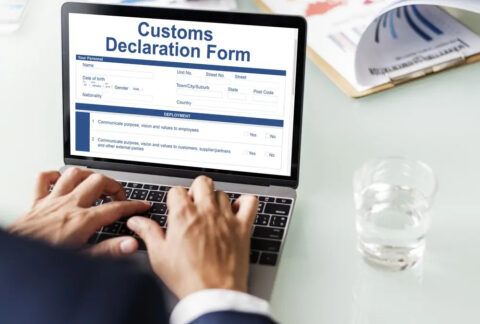 Businessman filling in Customs Declaration Form on laptop