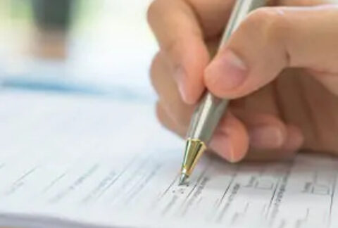 Hand filling out form with pen