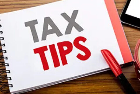 Open notebook on desk with 'tax tips' written on page