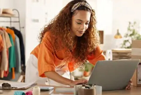 Businesswoman standing over desk using laptop