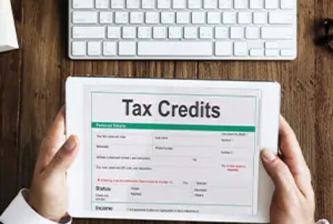Hands holding a tablet with tax credits page on screen