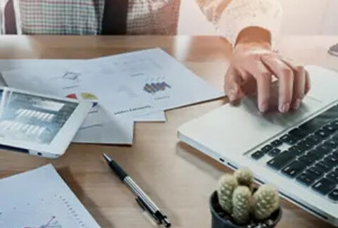 Businessman working on laptop at desk with papers