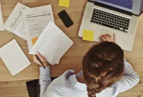 Businesswoman working on laptop at desk with papers