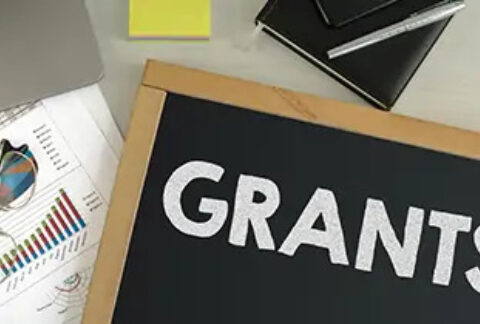 Blackboard with 'Grants' written on it on top of paperwork
