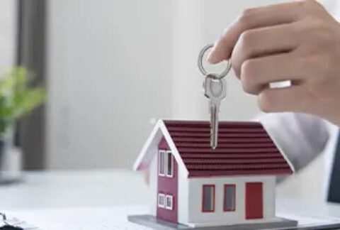 Hand holding a set of keys over a model house