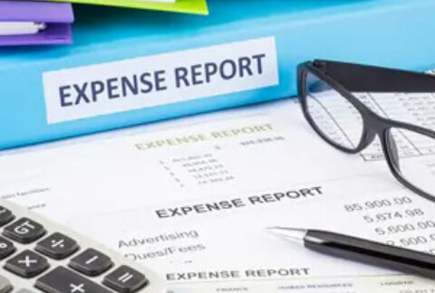 Expense report documents in front of a folder labelled 'expense report', with a pen, calculator and pair of glasses on top