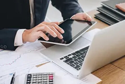 Businessman using tablet in front of laptop and calculator on desk