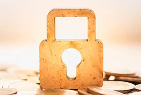 Gold padlock sitting upright on top of a pile of coins