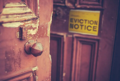 Double doors, one open one closed, with 'eviction notice' sign on front