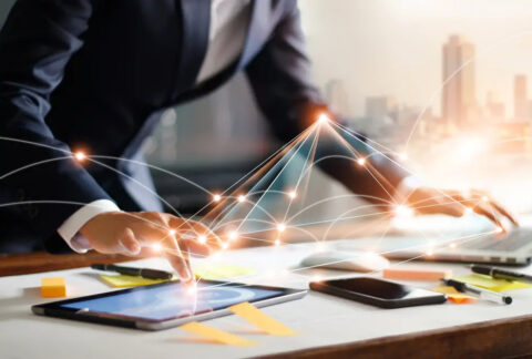 Businessman using tablet with one hand and laptop with the other, overlayed with network image