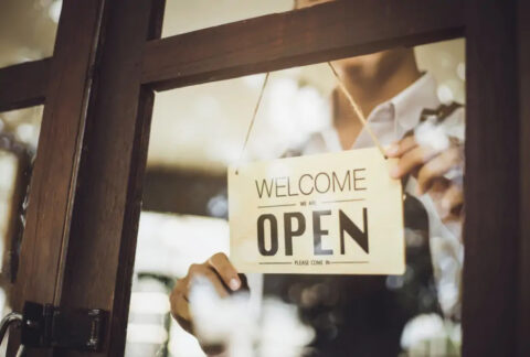 Business owner turning 'open' sign through glass door