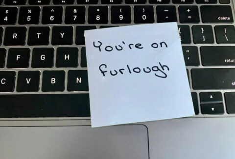 Laptop keyboard with post-it note on top that says 'you're on furlough'