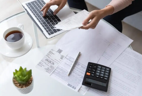 Businesswoman working on laptop on table next to documents and calculator