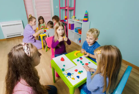 Children sitting around children's desks at a childcare facility doing crafts