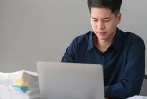 Businessman at desk working on laptop to prepare for payroll year-end