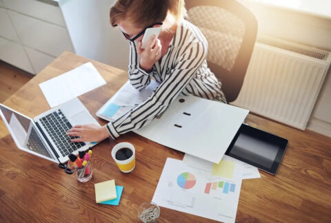 Businesswoman taking a phonecall while using laptop at desk