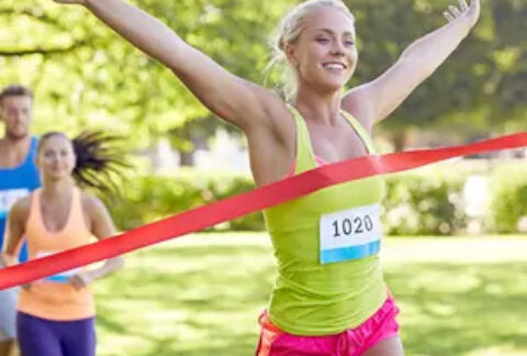 Woman crossing finish line in race and celebrating win