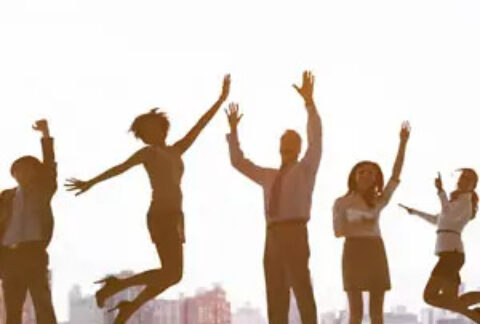 Five businesspeople jumping in celebration in front of cityscape background