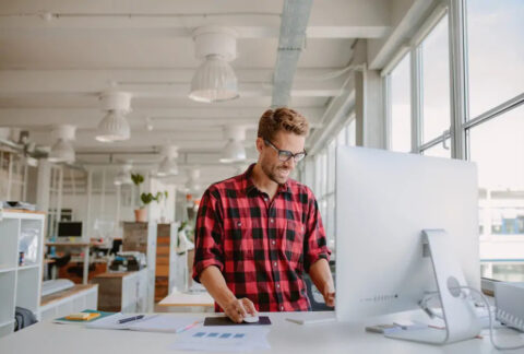 Businessman standing at desk in modern office using computer