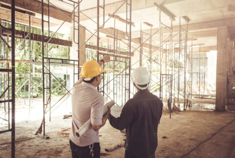 Two men in business clothing wearing hard hats at a construction site