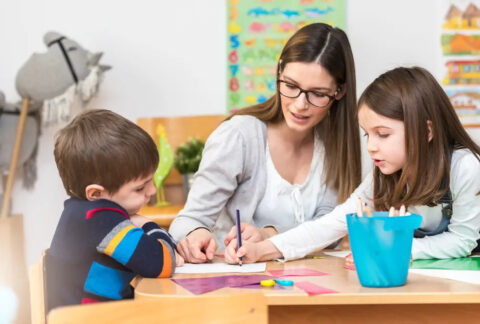 Mother sitting at table with two children colouring in