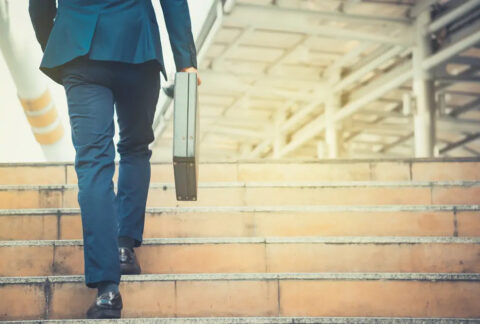 Businessman holding briefcase walking up stairs