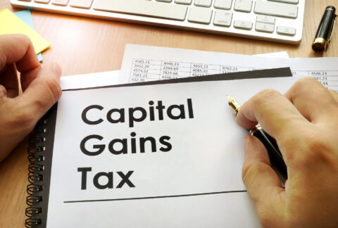 Hands around document with title 'Capital Gains Tax'
