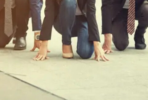 Three businesspeople crouching on ground as if about to start a race