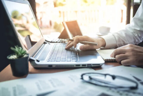 Businessman holding pen and using laptop