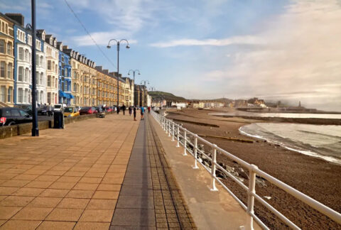 Promenade in Aberystwyth seaside resort with terraced houses on one side and an beach on the other