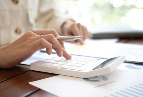 Businesswoman holing pen in hand and using calculator